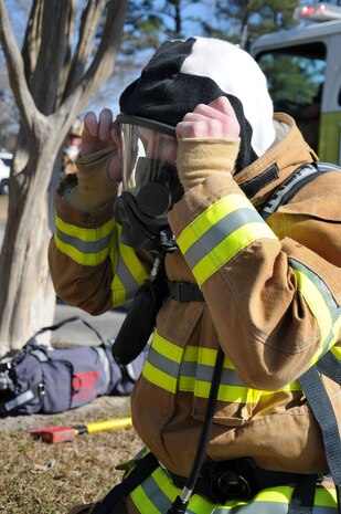 Senior Airman Craig Burnett dons his personal protective equipment gear as he prepares to rescue a fallen firefighter as part of a Rapid Intervention Team during an exercise at Joint Base Charleston – Weapons Station, Feb 2. The exercise was held to test the unit’s response times  as well as simulate putting out a fire at a home in the MenRiv Housing area.  Burnett is a member of the 628th Civil Engineering Squadron, Civil Engineer Fire Department. (U.S. Navy photo/Petty Officer 1st Class Jennifer Hudson)