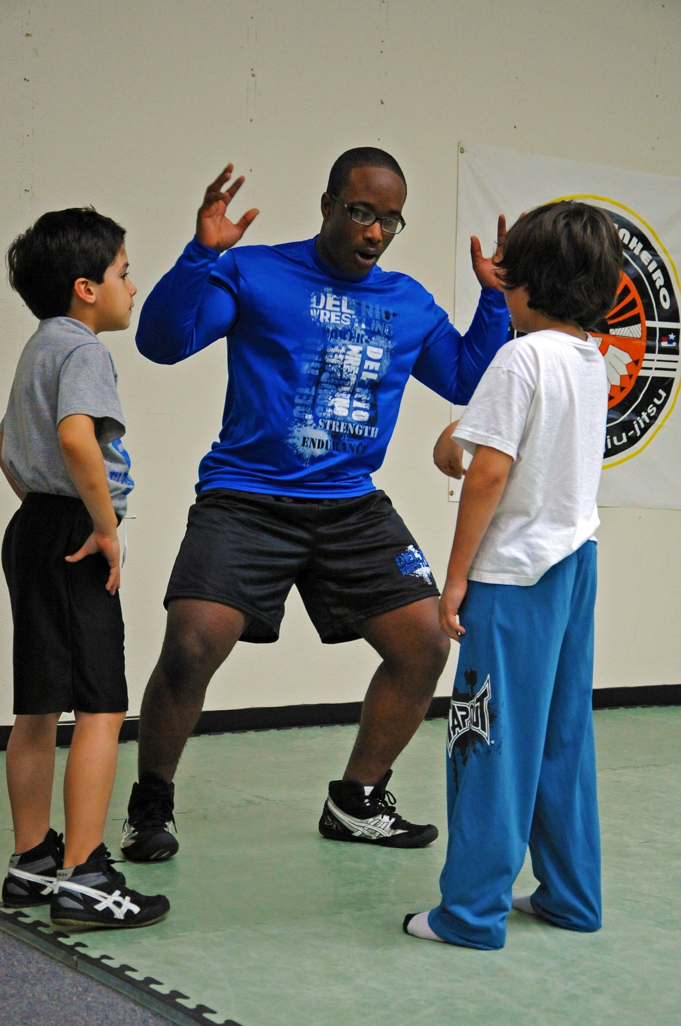 LAUGHLIN AIR FORCE BASE, Texas – 2nd Lt. Randall Mitchner, Del Rio Thunder coach, explains wrestling fundamentals to two of his students during a practice at the Eclipse Brazilian Jiu Jitsu gym in Del Rio, Texas, Feb. 2. The Del Rio Thunder wrestling team was recently created by Laughlin Airmen in late November after finding out there was no wrestling team for the middle school students. (U.S. Air Force photo/Senior Airman Scott Saldukas) 