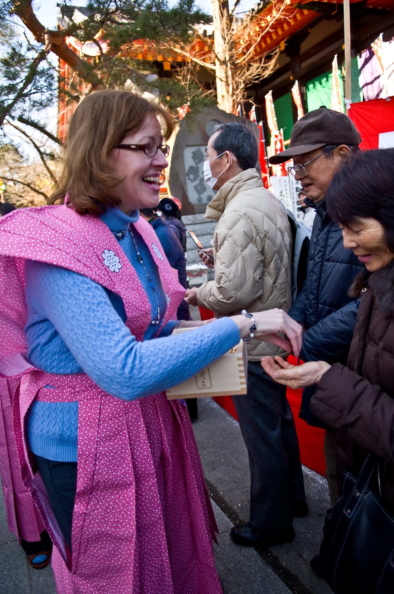 HINO CITY, Japan -- Nancy Feather, wife of 374th Airlift Wing Commander Col. Otto Feather, hands out roasted soy beans to guest attending the annual Bean Throwing Ceremony at Takahata Fudo Temple in Hino City, Japan, Feb. 3, 2012. It is believed that if an individual eats the number of beans equal to their age they will have a happy and healthy life. (U.S. Air Force photo/Airman 1st Class Krystal M. Garrett)