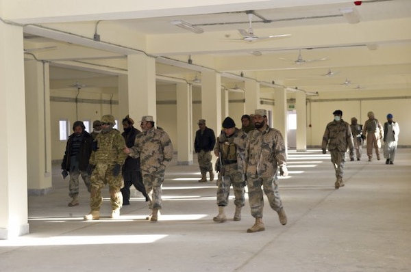 Afghan Border Police leaders walk through open bay barracks at the Islamcha garrison. With them (in MultiCam uniform) is mentor Maj. Douglas Ingold.