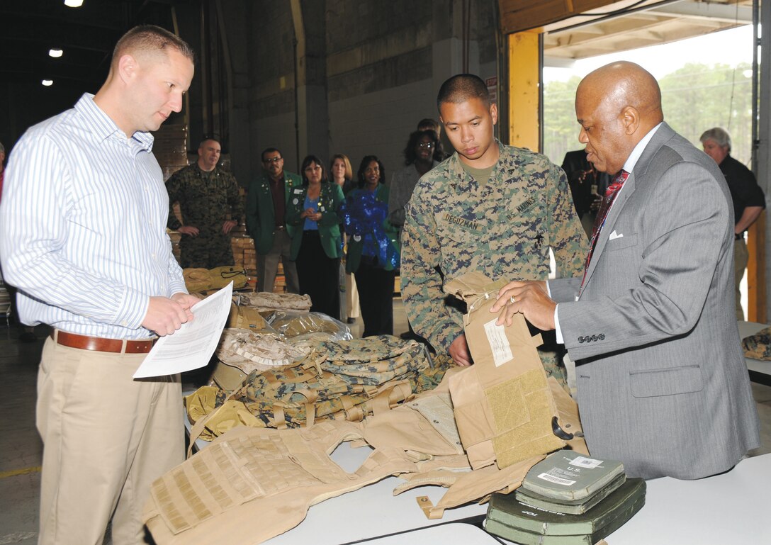 Walter Miller, a senior logistics management specialist contractor, instructs Cpl. Ghiemar DeGuzman, motor transport mechanic, Marine Corps Logistics Command, on his equipment as Jeremy Meyer, a logistics management specialist contractor, far left, watches. Miller and Meyer are among four staff who operates the new Albany Individual Issue Facility.