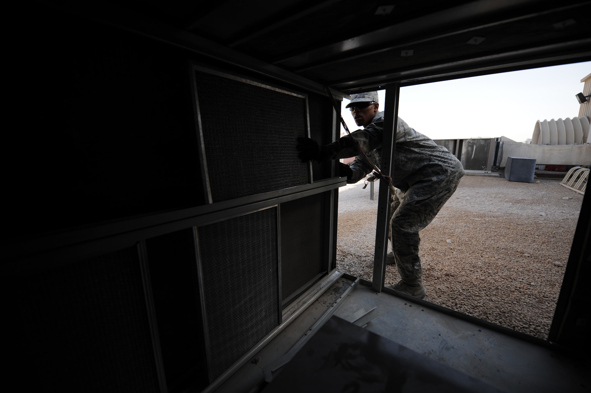 SOUTHWEST ASIA – Airman 1st Class Terence Myers, 379th Expeditionary Civil Engineer Squadron heating, ventilation, and air conditioning technician and native of Danville, Va., re-installs air conditioning unit filters here Feb. 7, 2012. The temperatures here routinely break 100 degrees Fahrenheit during the summer, so preventative inspections and maintenance ensure the units function year-round. (U.S. Air Force photo/Staff Sgt. Nathanael Callon)