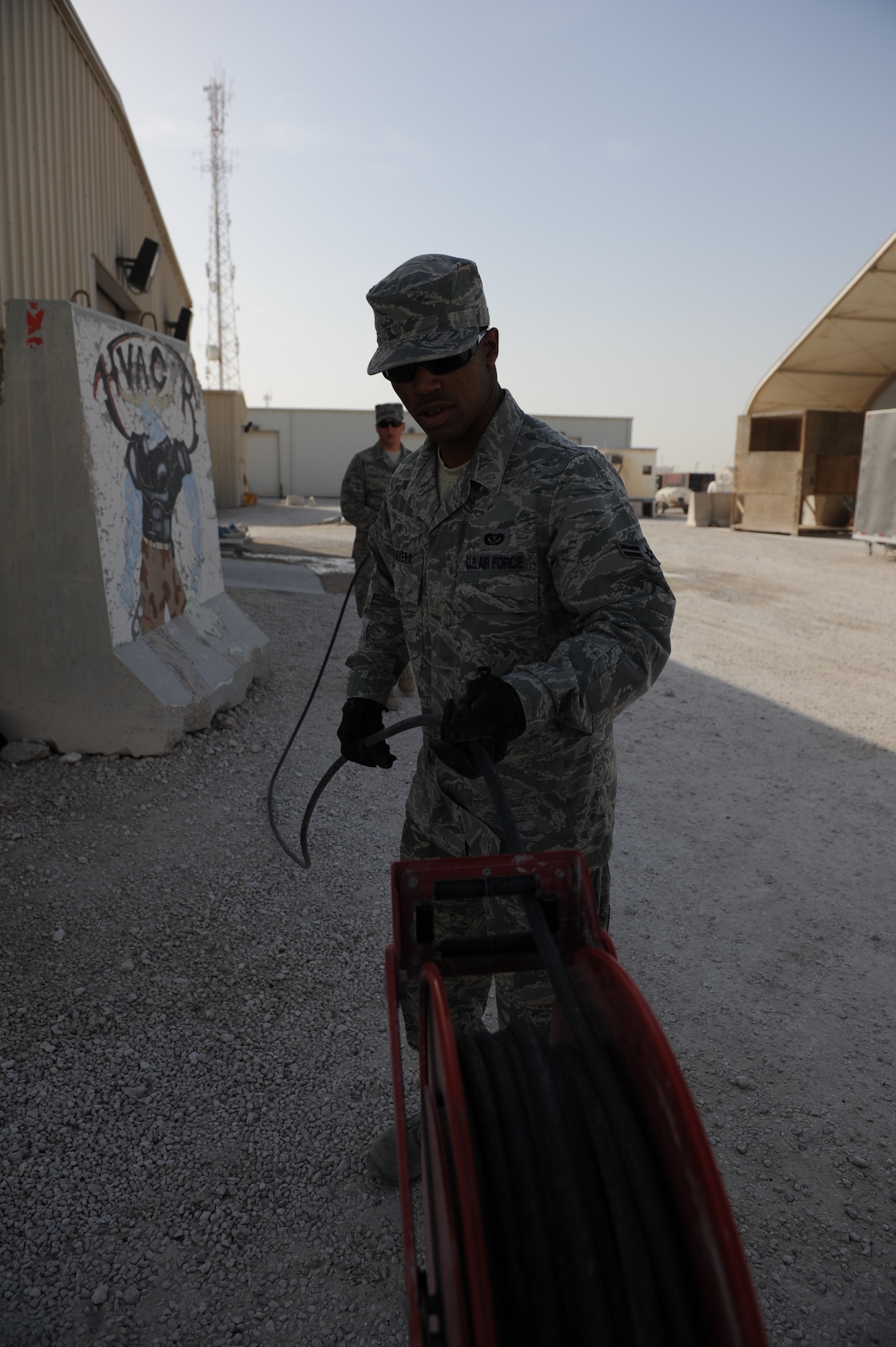 SOUTHWEST ASIA – Airman 1st Class Terence Myers, 379th Expeditionary Civil Engineer Squadron heating, ventilation, and air conditioning technician and native of Danville, Va., rolls up a pressure hose after spraying an air conditioning unit here Feb. 7, 2012. HVAC technicians spray the coils of the unit to extend its life and make the unit more efficient. (U.S. Air Force photo/Staff Sgt. Nathanael Callon)