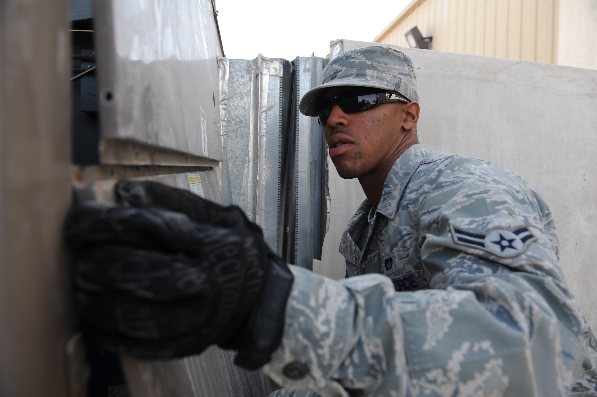SOUTHWEST ASIA – Airman 1st Class Terence Myers, 379th Expeditionary Civil Engineer Squadron heating, ventilation, and air conditioning technician and native of Danville, Va., removes a panel on an air conditioning unit to check a fan belt here Feb. 7, 2012. HVAC technicians clean the unit’s coils and filters, and check fan belts during a monthly inspection. (U.S. Air Force photo/Staff Sgt. Nathanael Callon)