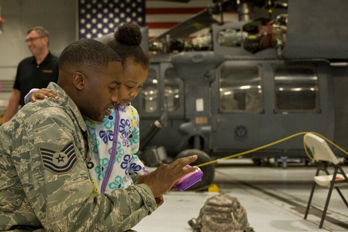 U.S. Air Force Tech. Sgt. Birdeal Ferguson, 763rd Maintenance Squadron member, plays with his daughter during a homecoming celebration Feb. 8, 2012, inside the 763rd Rescue Maintenance Squadron hangar on Nellis Air Force Base, Nev.  The returning 71 Airmen, most of whom are assigned to either the 66th Rescue Squadron or the 763rd Rescue Maintenance Squadron, comprised the last Air Force rescue unit stationed in Iraq prior to the withdrawal of U.S. forces in December 2011. (U.S. Air Force photo by Airman 1st Class Daniel Hughes)