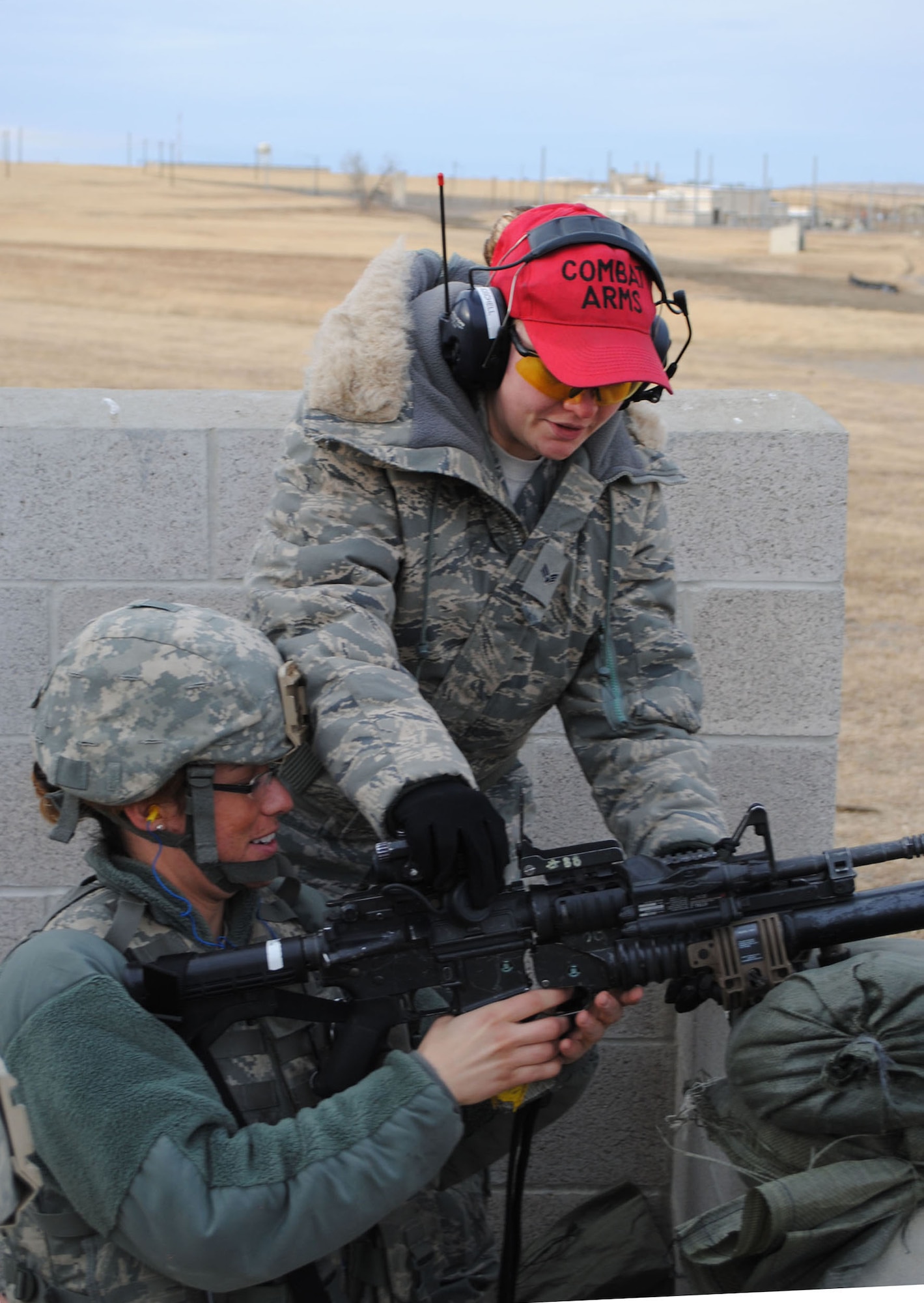 Senior Airman Chelsea Moschell, 341st Security Support Squadron CATM instructor, helps Airman 1st Class Rachel Harding, 341st Security Forces Squadron member, adjust her weapon for better accuracy. Moschell is one of many CATM instructors who are required to be qualified to shoot and teach every weapon system on Malmstrom. (U.S. Air Force photo/Airman 1st Class Cortney Paxton)