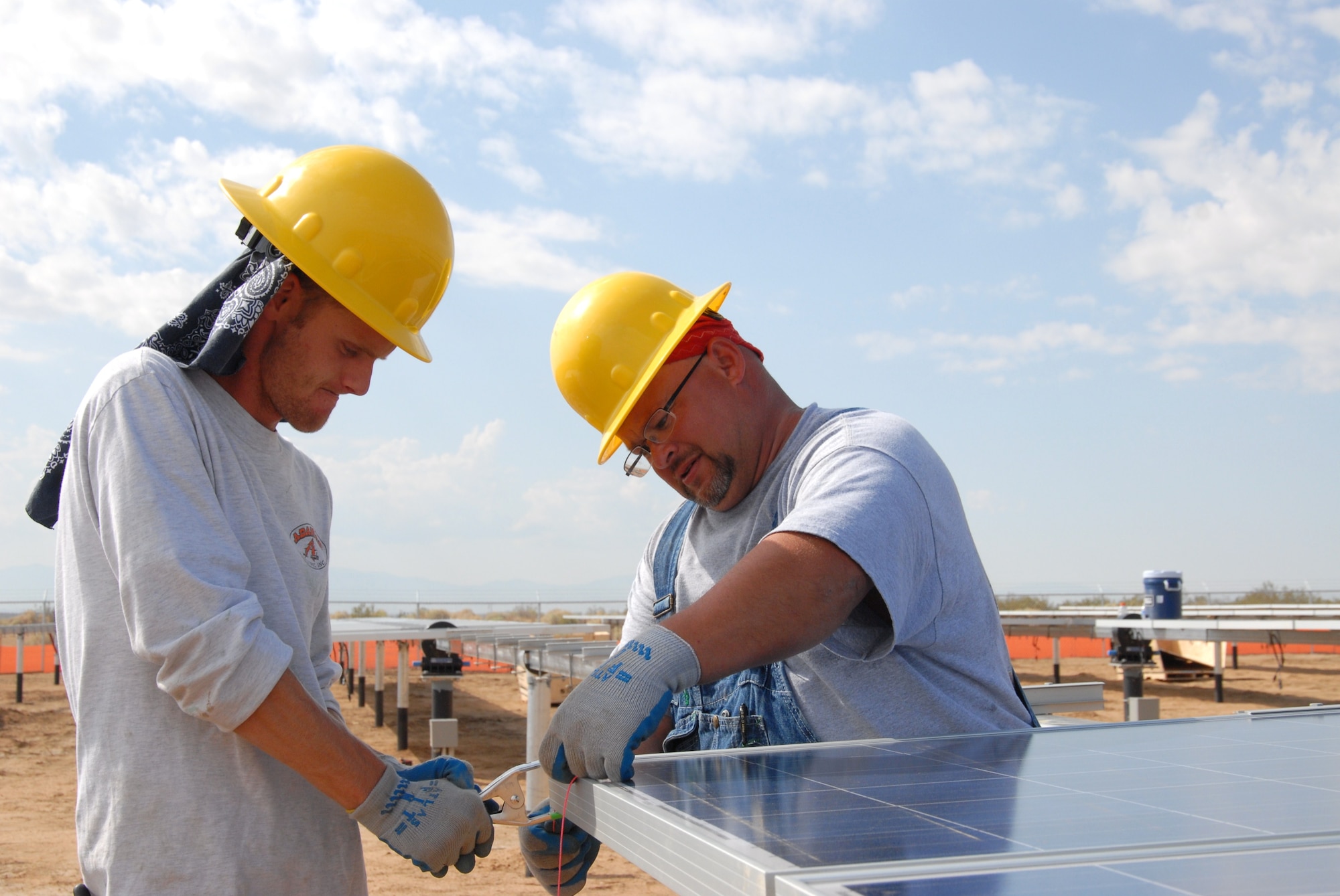 Construction workers attach a solar panel to a stand at Edwards Air Force Base, Calif., Feb. 2, 2012. This is one of three, one-megawatt solar arrays that are now complete and producing power. There are currently 50 renewable energy projects under construction at Air Force installations around the world. (U.S. Air Force photo/Dawn Waldman)