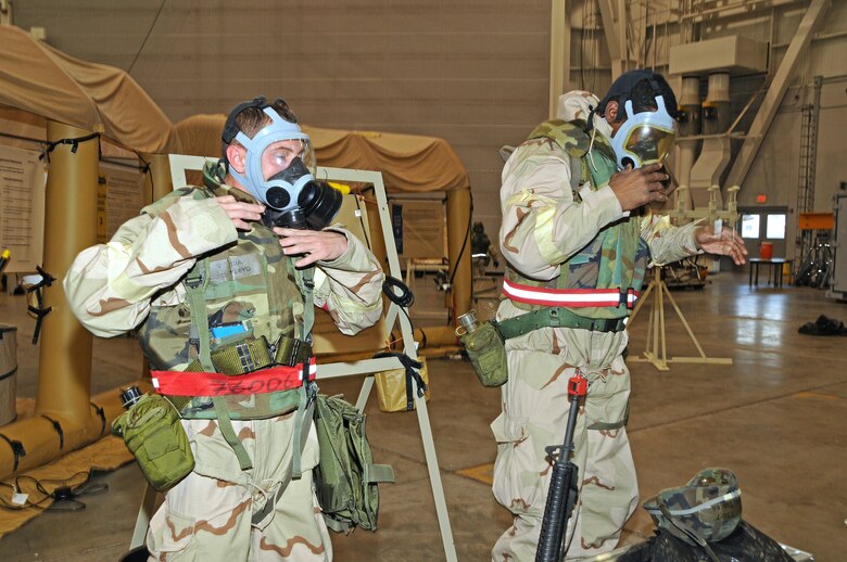 National Guard Senior Airman Farris Floyd and National Guard Tech. Sgt. Anthony Fields don their MCU-2 protective masks during a simulated chemical attack at Gulfport Combat Readiness Training Center, MS., Feb. 2, 2012. As part of the Air Mobility Command's Operational Readiness Inspection, Floyd and Fields must show they are able to survive and operate in a chemical environment by donning their chemical ensemble.  (National Guard photo by Staff Sgt. Noel Velez Crespo /released).