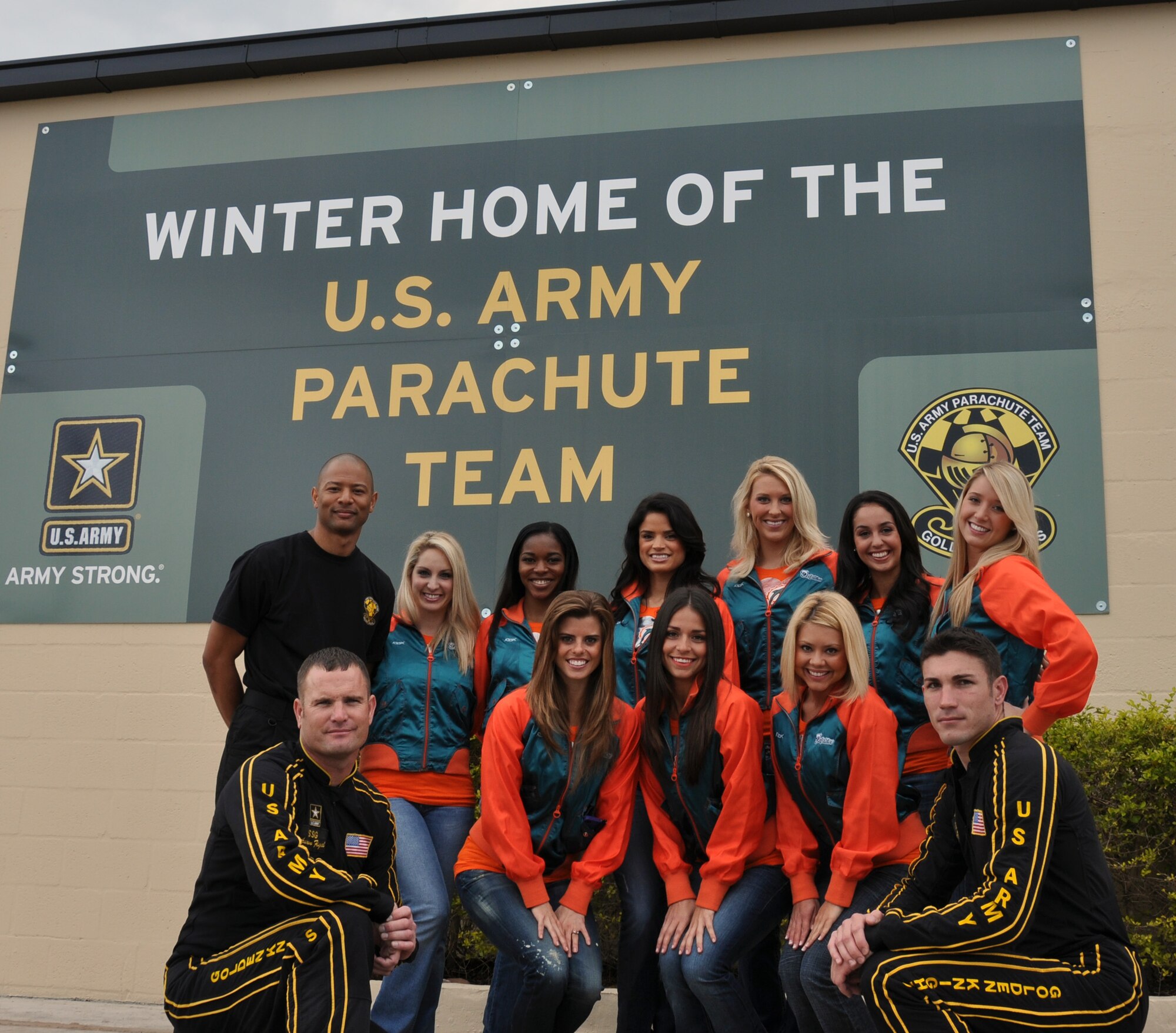 Members from the MIami Dolphins Cheerleaders pose for a picture with the U.S. Army Parachute team, the Golden Knights, during a visit to Homestead Air Reserve Base, Feb. 9. The visit co-insides with the Miami Dolphins effort to support the troops from different military installations. (U.S. Air Force photo/Senior Airman Katie Spencer)