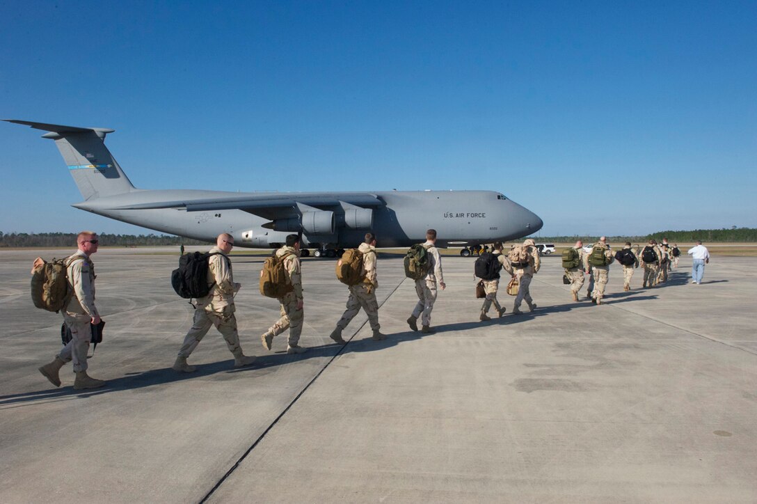 Members of the Coast Guard Port Security Unit 308 walk across the tarmac Jan. 28, 2012, at Stennis International Airport, Miss., in support of Operation Bold Alligator 2012. The team boarded a C-5M Super Galaxy, flown by members of the Air Force Reserve Command's 512th Airlift Wing, based at Dover Air Force Base, Del. Operation Bold Alligator, which takes place off the coasts of Virginia, North Carolina, and Florida, is the largest amphibious assault exercise in a decade. (U.S. Coast Guard photo/Petty Officer 2nd Class Michael Anderson)
