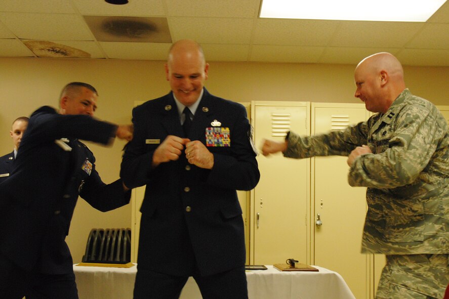 Lt. Col. Timothy Martz, 94th Security Forces Squadron commander, and Capt. Jimmie D. Mills "tag" Chief Master Sgt. DeMaine Milbach, 94 SFS manager, during his promotion and pin-on ceremony Feb. 4, at the base firing range. Milbach is succeeding Chief Master Sgt. Wendell Peacock, former 94 SFS manager and current 94th Airlift Wing Command Chief Master Sgt. (U.S. Air Force photo/Senior Airman Spencer Gallien)