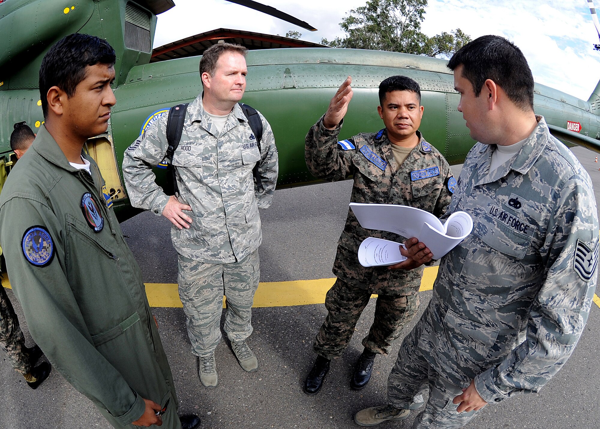 Honduran Air Force Sub-official Master 1st Class Juan Carlos Rodriguez Rivas, helicopter flying crew chief, and Senior Master Sgt. Jason Hood, 571st Mobility Support Advisory Squadron helicopter crew chief and air advisor, listens in as FAH Sub-official Master 2nd Class Enrique Hernandez Sanchez, FAH inspector, and Technical Sgt. Ruben Sigala, Inter-American Air Forces Academy instructor, discusses the inflight operational check of the radar altimeter system at Col. Hernán Acosta Mejia Air Base, Tegucigalpa, Honduras, Feb. 6.  (U.S. Photo by Tech. Sgt. Lesley Waters)