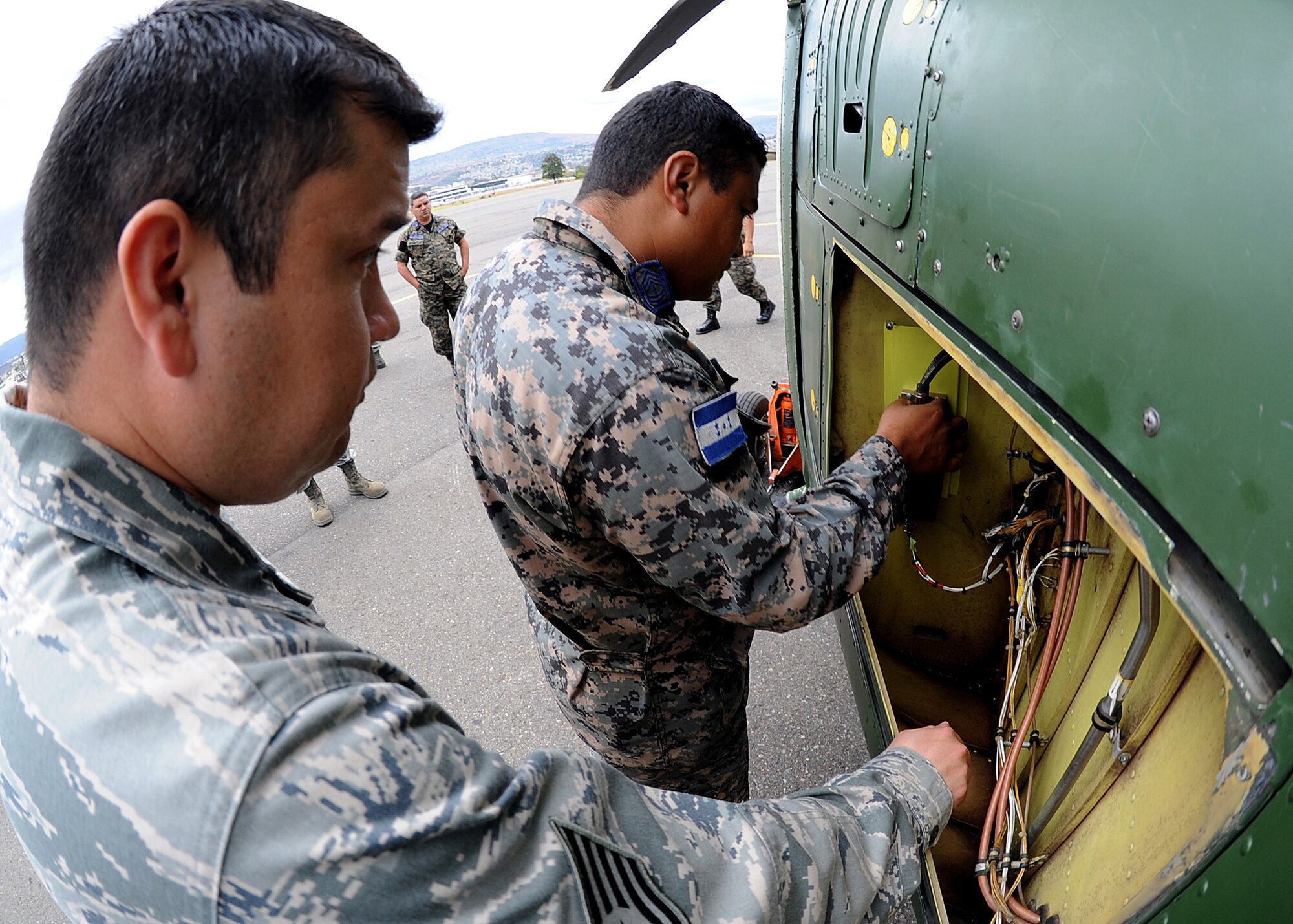 Technical Sgt. Ruben Sigala, Inter-American Air Forces Academy instructor, 318th Training Squadron, Lackland AFB, Texas, looks on as Honduran Air Force Sergeant Major Fernando David Fonseca, aircraft electrician, makes final wiring adjustments during the installation of the radar altimeter at Col. Hernán Acosta Mejia Air Base, Tegucigalpa, Honduras, Feb. 6.  (U.S. Photo by Tech. Sgt. Lesley Waters)