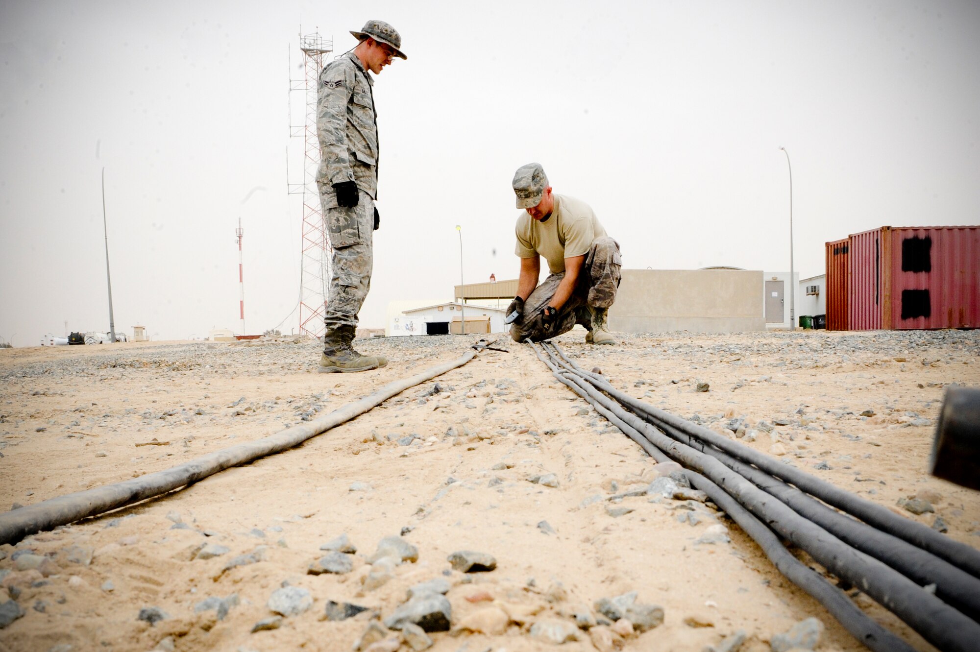 SOUTHWEST ASIA -- Airman 1st Class Zachary Salts and Staff Sgt. Christopher Billings, 332nd Expeditionary Communication Squadron infrastructure shop members, check a cable for activity at an undisclosed location in Southwest Asia, Feb. 9, 2012. The cables are checked by sending a signal from one point to another. Salts is deployed from the Royal Air Force Lakenheath, England, and is a native of Las Vegas. Billings is deployed from Yokota Air Base, Japan, and is a native of Knoxville, Tenn. (U.S. Air Force photo by Staff Sgt. Joshua J. Garcia/Released)