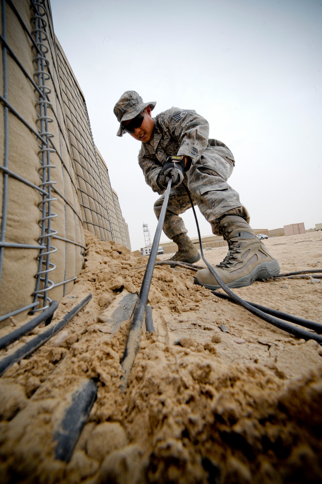 SOUTHWEST ASIA – Staff Sgt. Kyle Otsuka, 332nd Expeditionary Communication Squadron infrastructure shop, pulls a cable out of the ground at an undisclosed location in Southwest Asia, Feb. 9, 2012. The infrastructure locates and disposes inactive cables base. Otsuka is deployed with the Hawaii Air National Guard and is a native to Hilo, Hawaii. (U.S. Air Force Photo by Staff Sgt. Joshua J. Garcia/Released)