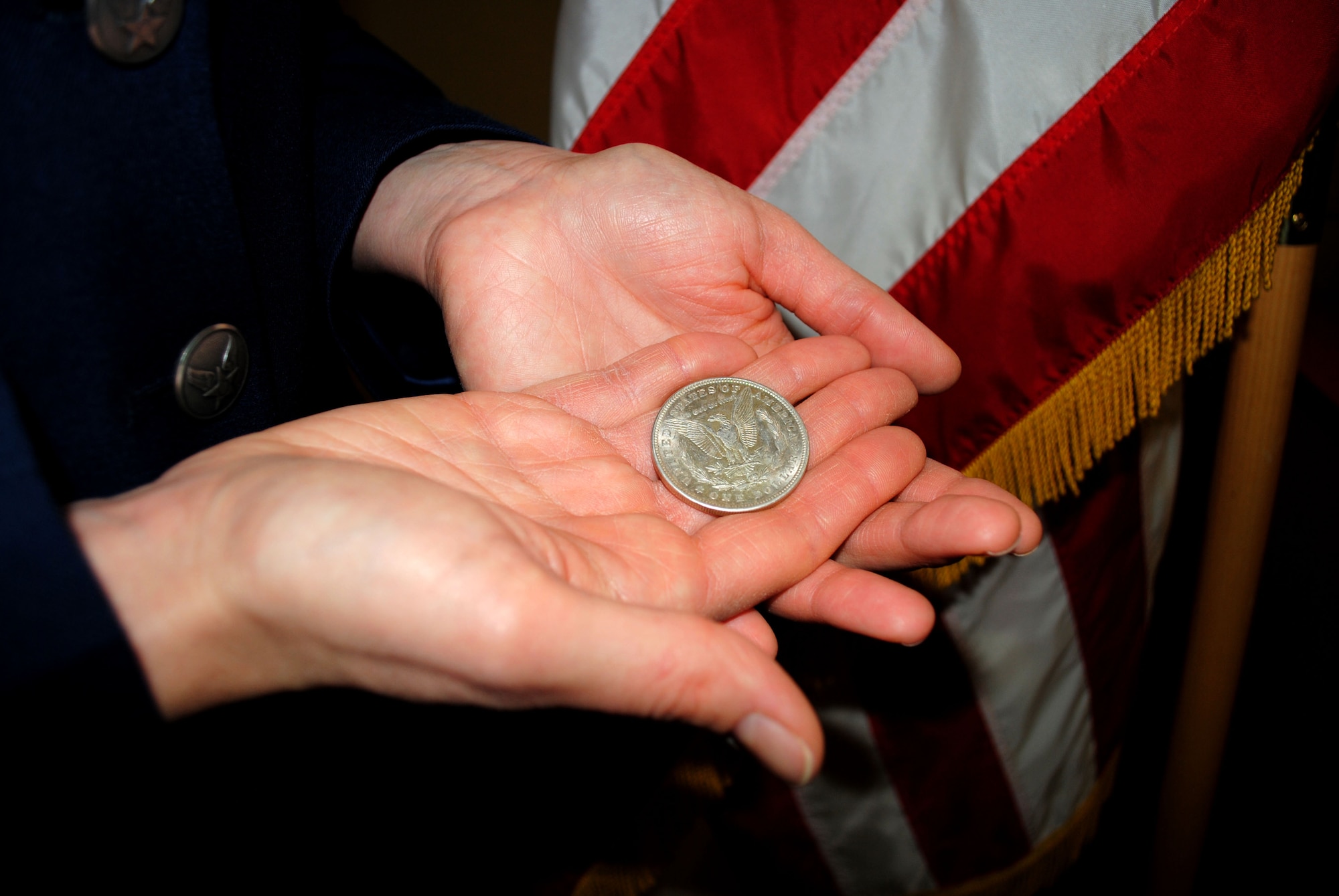 Former Staff Sgt. Donna Tluczek, holds in her hand a silver dollar destined for her husband, Tech. Sgt. Pawel Tluczek, who rendered the new second lieutenant her first enlisted saluted from more than 8,000 miles away via a live Internet broadcast Feb. 2, 2012, at the Air Force ROTC Detachment 610 headquarters on the University of North Dakota campus. Military tradition dictates that an officer give a silver dollar to the first enlisted member to offer a salute. (U.S. Air Force photo/Senior Airman Luis Loza Gutierrez)