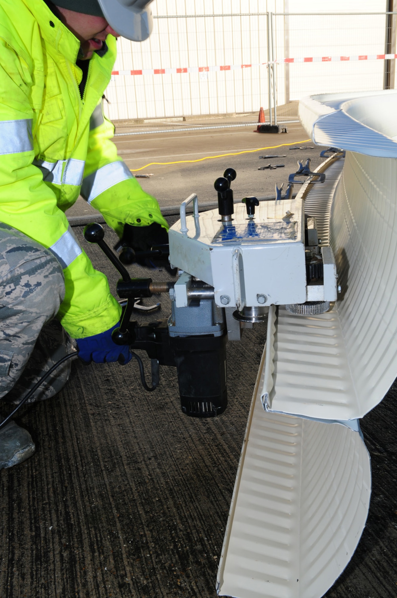 RAF MILDENHALL, England -- Staff Sgt. Ryan Kull, 435th Construction and Training Squadron Military Construction Flight, from a geographically-separated unit near Ramstein Air Base, Germany, uses a 75-pound seaming machine to join together crimped edges of steel panels, to form a pick Jan. 27, 2012. The steel panels are first held together by clamps before being crimped and seamed by the machine. When five panels have been joined together to form a pick, it is then attached to a crane and transferred to the K-Span. (U.S. Air Force photo/Karen Abeyasekere)