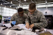 Airman 1st Class Daniel McDuffie and William Cruz Torres, 2nd Maintenance Squadron Aerospace Ground Equipment Flight, read a technical order while working on a piece of equipment on Barksdale Air Force Base, La., Feb. 7. Each piece of equipment has its own T.O. or procedure on how to maintain it. (U.S. Air Force photo/Airman 1st Class Benjamin Gonsier)(RELEASED)