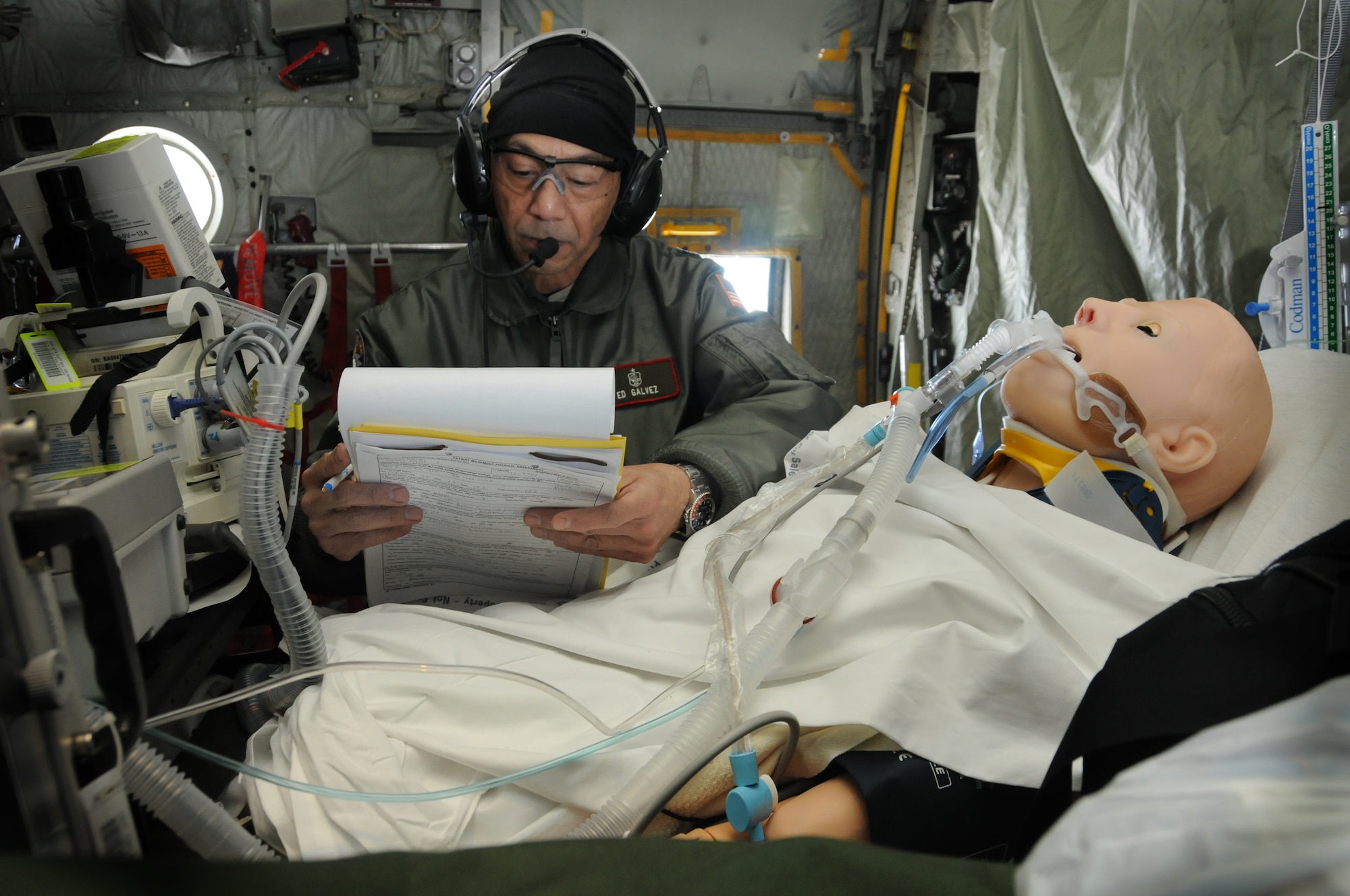 Lt. Col. Ed Galvez, trauma nurse specialist, reviews HAL's medical chart during a Critical Care Air Transport Team exercise on board a C-130 Hercules February 4. HAL is a male manikin-simulator, used for training purposes.  (Air Force Photo/Tech. Sgt Bob Sommer)