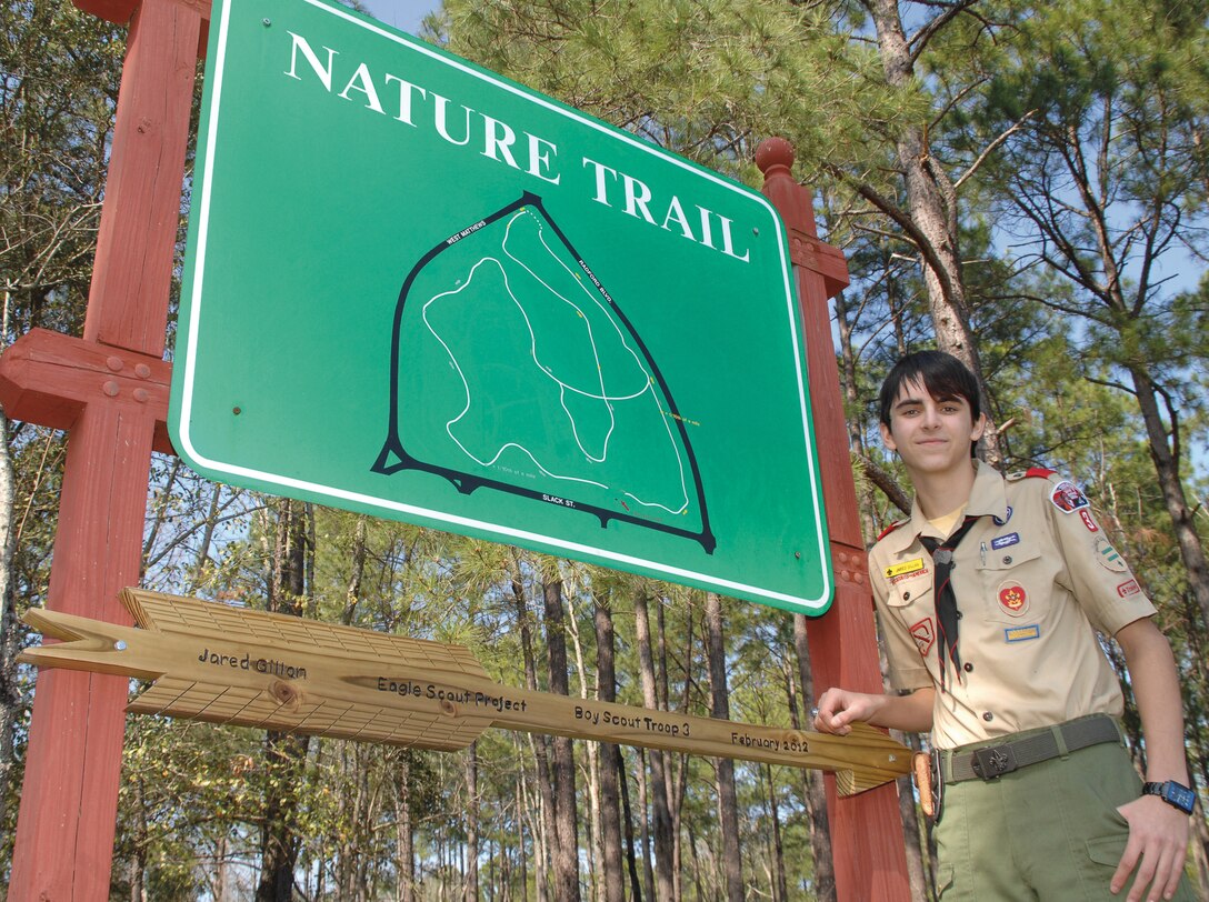 Jared R. Gillan, a Boy Scout with Boy Scout Troop 3 of Albany, Ga., showcases a new sign at one of Marine Corps Logistics Base Albany’s nature trails, Feb. 4. He and more than 40 volunteers, sprused up one of the trails between Building 3500 and Maintenance Center Albany for an Eagle Scout project.