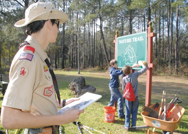 Jared R. Gillan observes Boy Scouts as they clean the sign at the nature trail’s entrance, Feb. 4.