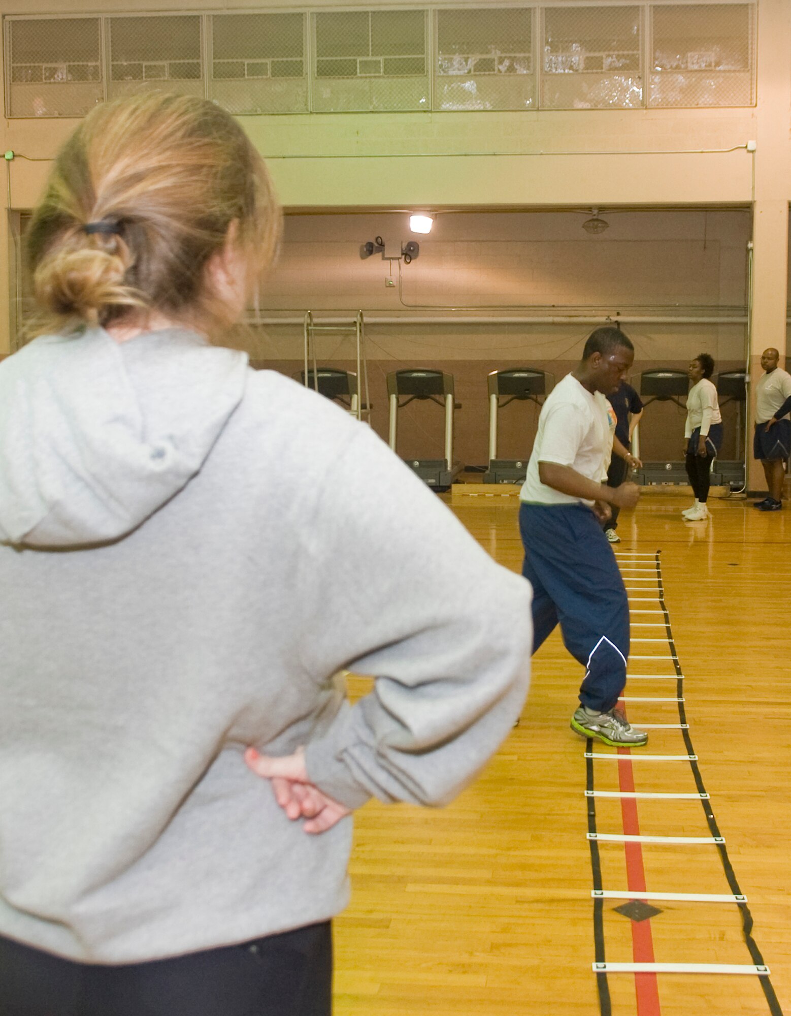 Leah Beckham, 2nd Medical Operations Squadron Health and Wellness Center health and fitness specialist, observes as Airman 1st Class Drew Burrell, 2nd Force Support Squadron, performs exercises on an agility ladder during the Run Improvement Program on Barksdale Air Force Base, La., Feb. 10. Beckham developed RIP to help improve people's fitness by focusing on safe training techniques over quick fix training programs. (U.S. Air Force photo/Senior Airman Kristin High)(RELEASED)