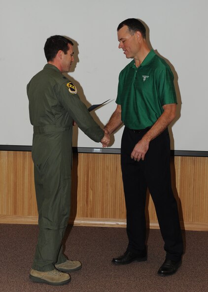 Lt. Col. Marc London, 7th Bomb Wing, presents Mike Simpson, 7 BW, with the February 7 BW superior performer award, Feb. 9,  2012, at Dyess Air Force Base, Texas. Every month each group selects one person or team who has shown superior performance to be recognized in front of wing leadership. (U.S. Air Force photo by Airman 1st Class Peter Thompson/Released) 