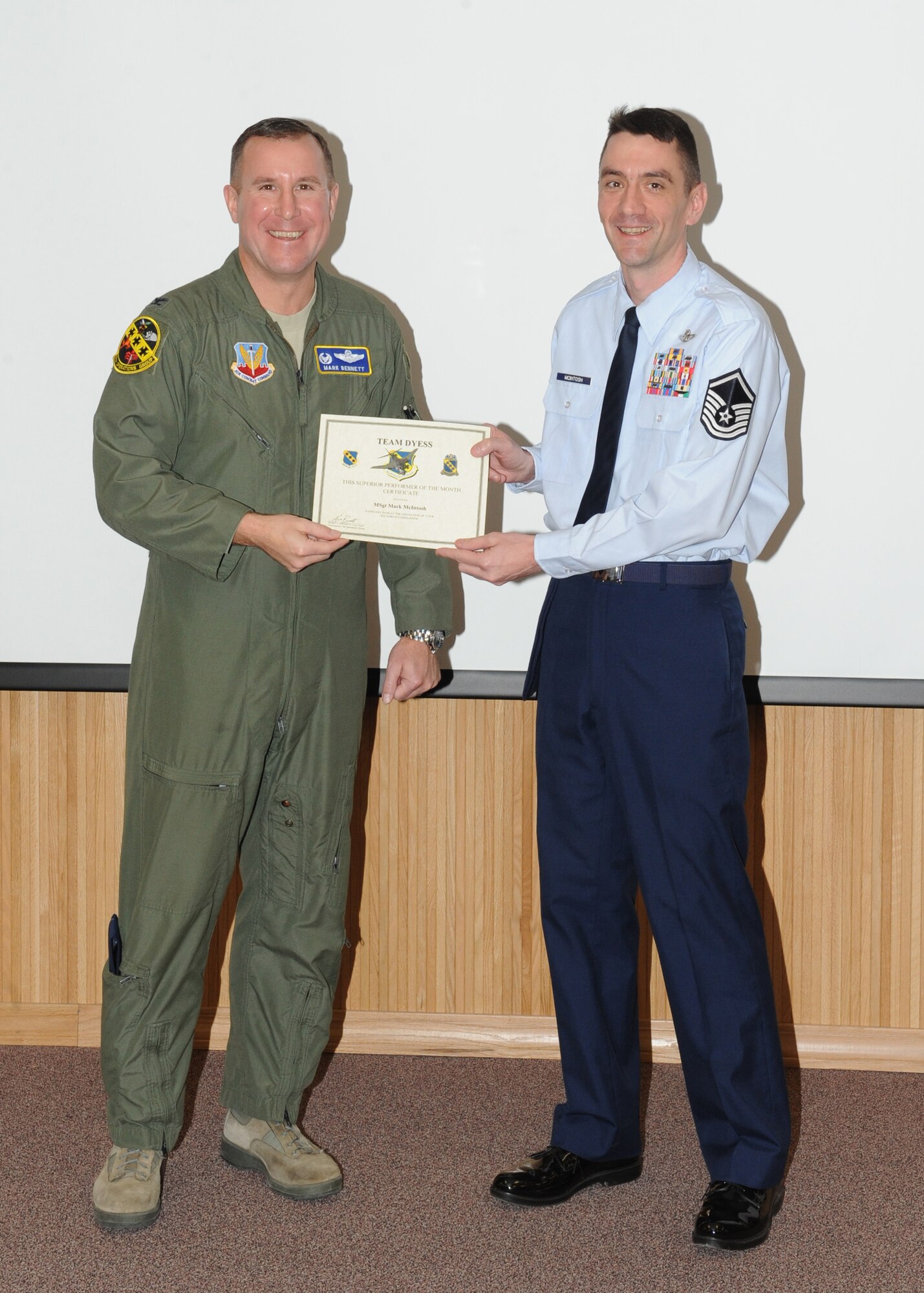 Col. Mark Bennett, 7th Operations Group commander, presents Master Sgt. Mark McIntosh, 7 OG, with the February 7 OG superior performer award, Feb. 9,  2012, at Dyess Air Force Base, Texas. Every month each group selects one person or team who has shown superior performance to be recognized in front of wing leadership. (U.S. Air Force photo by Airman 1st Class Peter Thompson/Released) 
