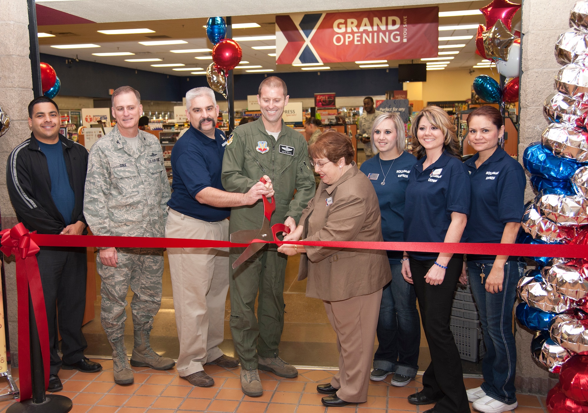 Col. Kevin Huyck, 49th Wing vice commander, cuts the ribbon at the grand opening of the Mini Mall Express here Feb. 10 with Phyllis Keister, Holloman Exchange General Manger, Matthew Clark, shift manager, Col. Robert Cole, 49th Mission Support Group commander, and other Exchange employees. Everything there is new, from the fixtures on the lights to the floor. Hours are Monday through Friday, 5:30 a.m. to midnight and Saturdays and Sundays from 8:30 a.m. to midnight. (U.S. Air Force photo by Airman 1st Class Colin Cates/Released)