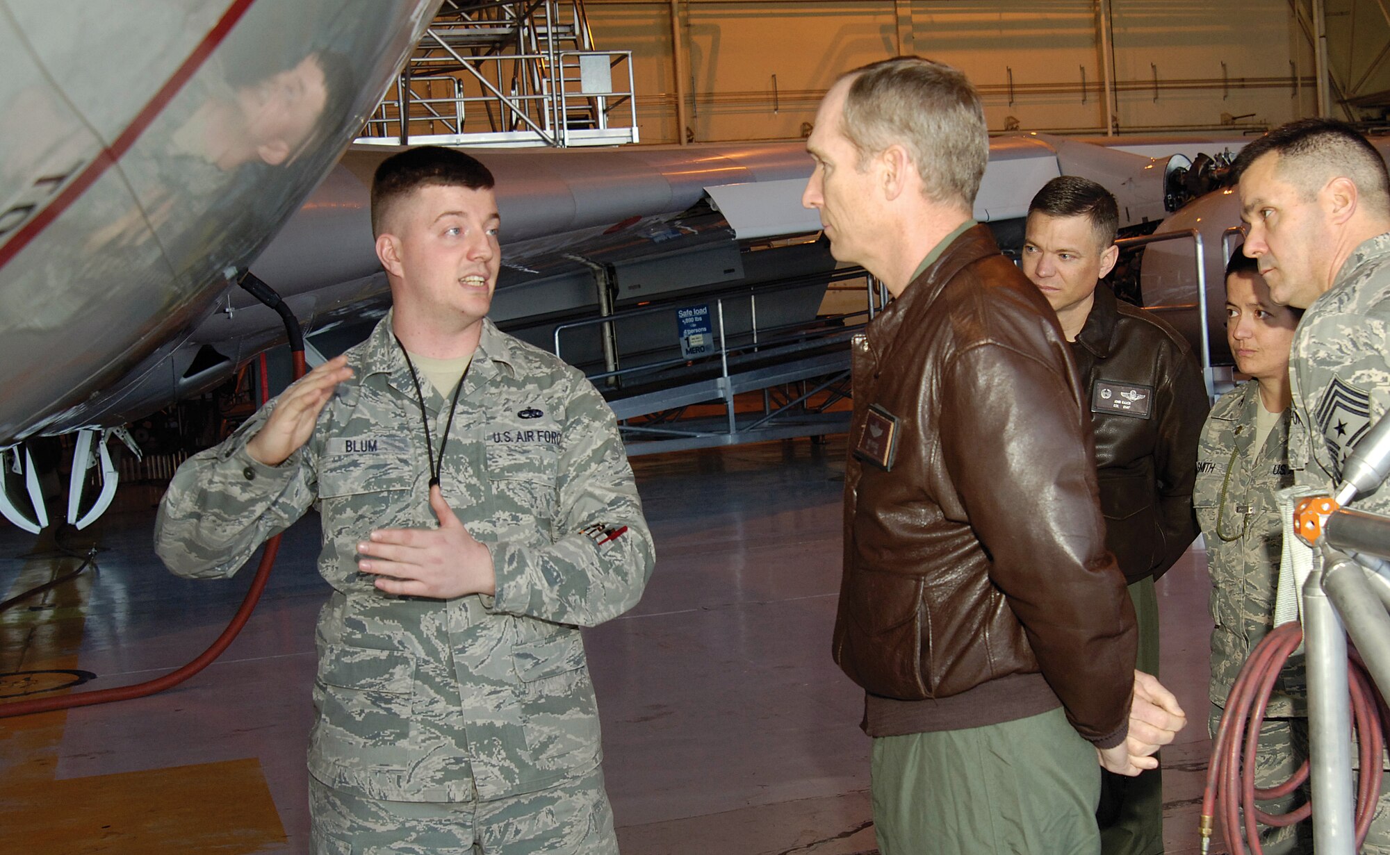 U.S. Air Force Tech. Sgt. Timothy Blum, 552nd Maintenance Squadron crew chief, talks with Gen. Mike Hostage, commander of Air Combat Command, about the familiar aircraft challenges of battling corrosion on the E-3 Sentry in one of several briefings during the commander’s three-day Tinker visit.  The general met with Airmen throughout the 552nd Air Control Wing Jan. 25-27, thanking them at every opportunity for their service. Behind Hostage are, back from left; Col. John Rauch, 552nd ACW commander; Col. Stella Smith, 552nd Maintenance Group commander; and Command Chief Master Sgt. Eddie Compton, 552nd ACW command chief. (Air Force photo by Margo Wright)