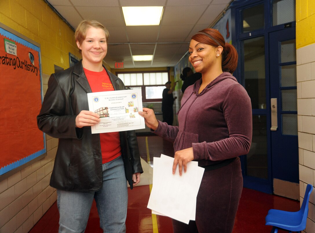 WASHINGTON -- Marine Sgt. Angela Palm, Marine Corps Base Quantico sergeants course cyber security specialist, receives a certificate of appreciation from Staff Sgt. Natosha Mansker, Joint Base Andrews 779th Medical Group dental technician, for helping makeover C.W. Harris Elementary School Feb. 4. Military personnel from the National Capitol Region and their families helped by painting hallways and all of the doors, power-washing the exterior, removing grafitti and setting up classrooms. (U.S. Air Force photo/Senior Airman Amber Russell)