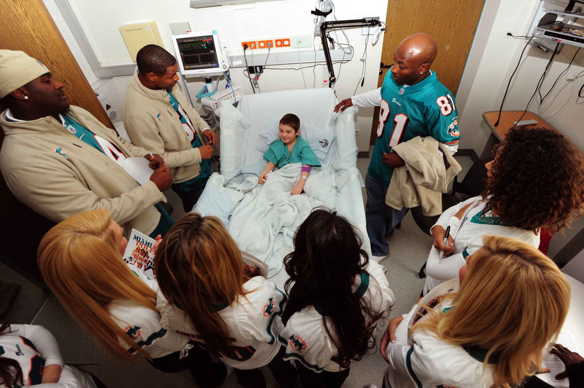 The Miami Dolphin cheerleaders and former professional football players meet with Richard Braun, a patient at the Landstuhl Regional Medical Center for military members as part of an Armed Forces Entertainment tour at Ramstein Germany, Feb 09, 2012. Former members from the Miami Dolphins and six of their cheerleaders came here to visit with troops and throw down on a little flag football. (U.S. Air Force photo by Senior Airman Aaron-Forrest Wainwright)
