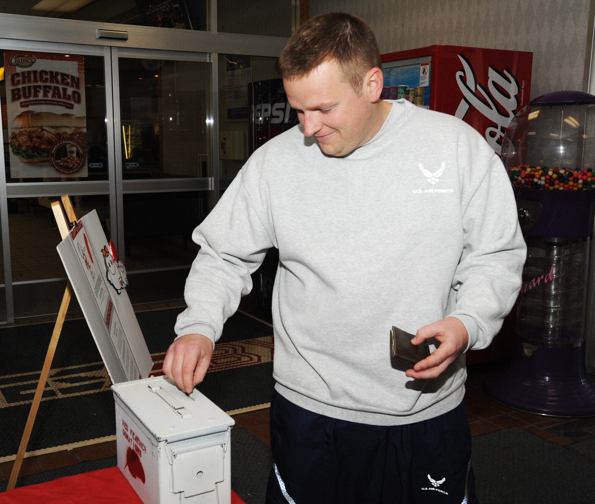 MISAWA AIR BASE, Japan – Staff Sgt. David Skelton, 35th Maintenance Group unit deployment manager, donate to the Red Feather Campaign here, Feb. 9. After contributors donate, they are given a red feather, which is a symbol of courage and good conduct. Donations are raised through campaign drives at Cummings and Sollars Elementary Schools, base private organization contributions, sponsored base activities and money collected by volunteers at base-wide donation stands. (U.S. Air Force photo/Airman Kenna Jackson)