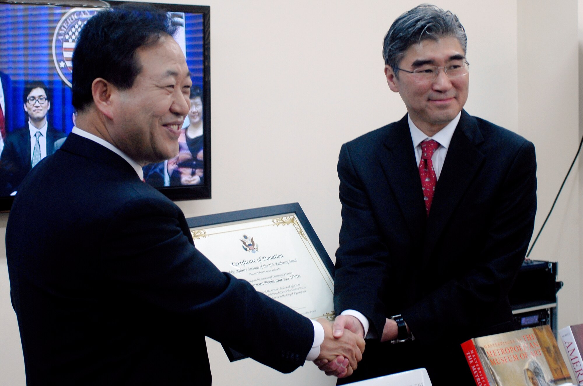 U.S. Ambassador to the Republic of Korea (right), Sung Kim, gives the Mayor of Pyeongtaek City, Kim Sung Ki, a donation of 411 books and 244 DVDs to go into the Songtan International Community Center located near Osan Air Base Feb. 9, 2012. The community center will offer information and referral service, cultural exchange events and educational programs to learn about other cultures to gain a better understanding of the growing number of foreigners in Korea. (U.S. Air Force photo/Capt. Cody Chiles)