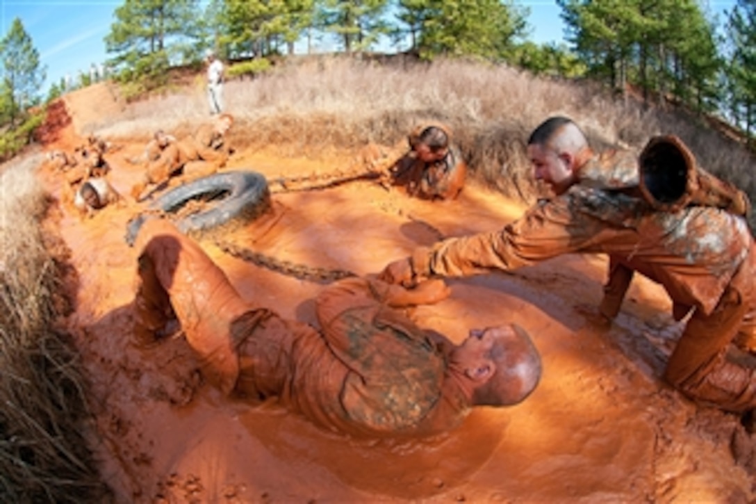 Officers help each other pull a truck tire through a mud pit during a team obstacle course as part of a Prop Blast at Fort Bragg, N.C., on Feb. 3, 2012.  