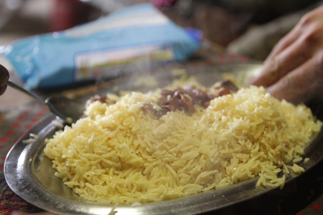 An Afghan National Army soldier eats a hot meal prepared by ANA Lance Cpl. Abdul Kabir, a cook with 3rd Tolai, 2nd Kandak, 2nd Brigade, 215th Corps, during lunch here, Feb. 10. The ANA soldiers purchased goods from local stores and prepared all food on post. U.S. Marines recently transferred authority of the local patrol base, Hanjar Yak, to the ANA. Every night, the ANA soldiers invited Marines to dinner.
