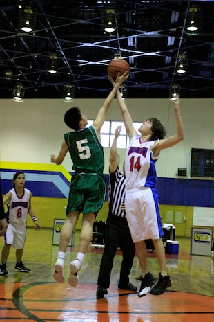 Shinji Hoshide, a Yanai Junior High School student and basketball player, and Michael Coletta, a Matthew C. Perry High School student and team Teddy Bears player, jump for the tip-off in the beginning of the championship game of the basketball tournament held in the IronWorks Gym sports court here Feb. 11.