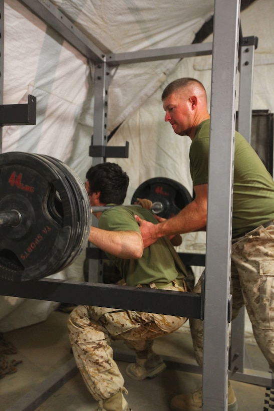 Staff Sgt. William A. Genochio, operations chief at Joint Sustainment Academy Southwest and native of Independence, Mo., helps an Afghan interpretter during a workout session, Aug. 25.