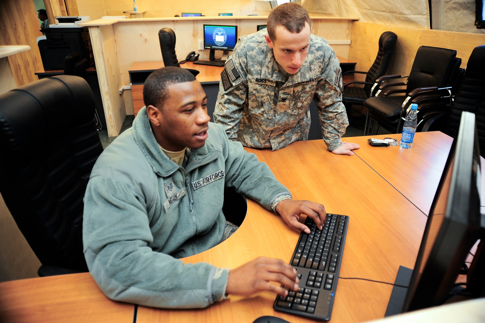 Staff Sgt. Preston Nealy installs computer software while Aviation Ordnanceman 2nd Class John Ross watches Jan. 25, 2012, at the Naval Forces Central Command Forward Headquarters Manas at the Transit Center at Manas, Kyrgyzstan. Nealy is a client systems technician with the 376th Expeditionary Communications Squadron, deployed here from MacDill Air Force Base, Fla. Ross is a liaison officer deployed here from the Naval Operations Support Center in Long Island, N.Y.(U.S. Air Force Photo/Staff Sgt. Angela Ruiz)