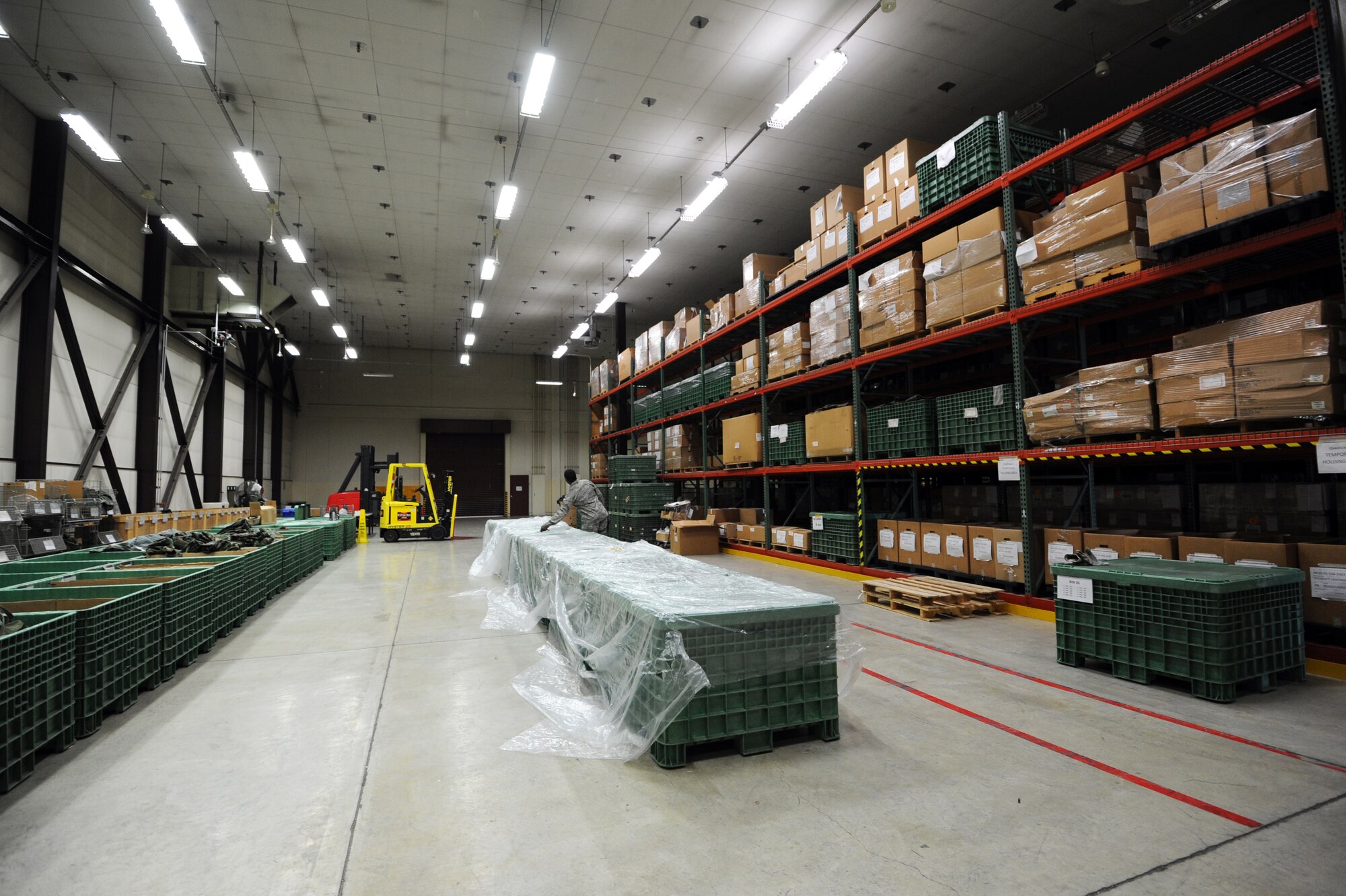 MISAWA AIR BASE, Japan -- Airman 1st Class Kevin Jackson, 35th Logistics Readiness Squadron individual protective equipment weapons journeyman, covers crates with a tarp for storage in the IPE warehouse here, Feb. 9. The crates contain extra Mission Oriented Protective Posture training gear. (U.S. Air Force photo/Airman 1st Class Kia Atkins)