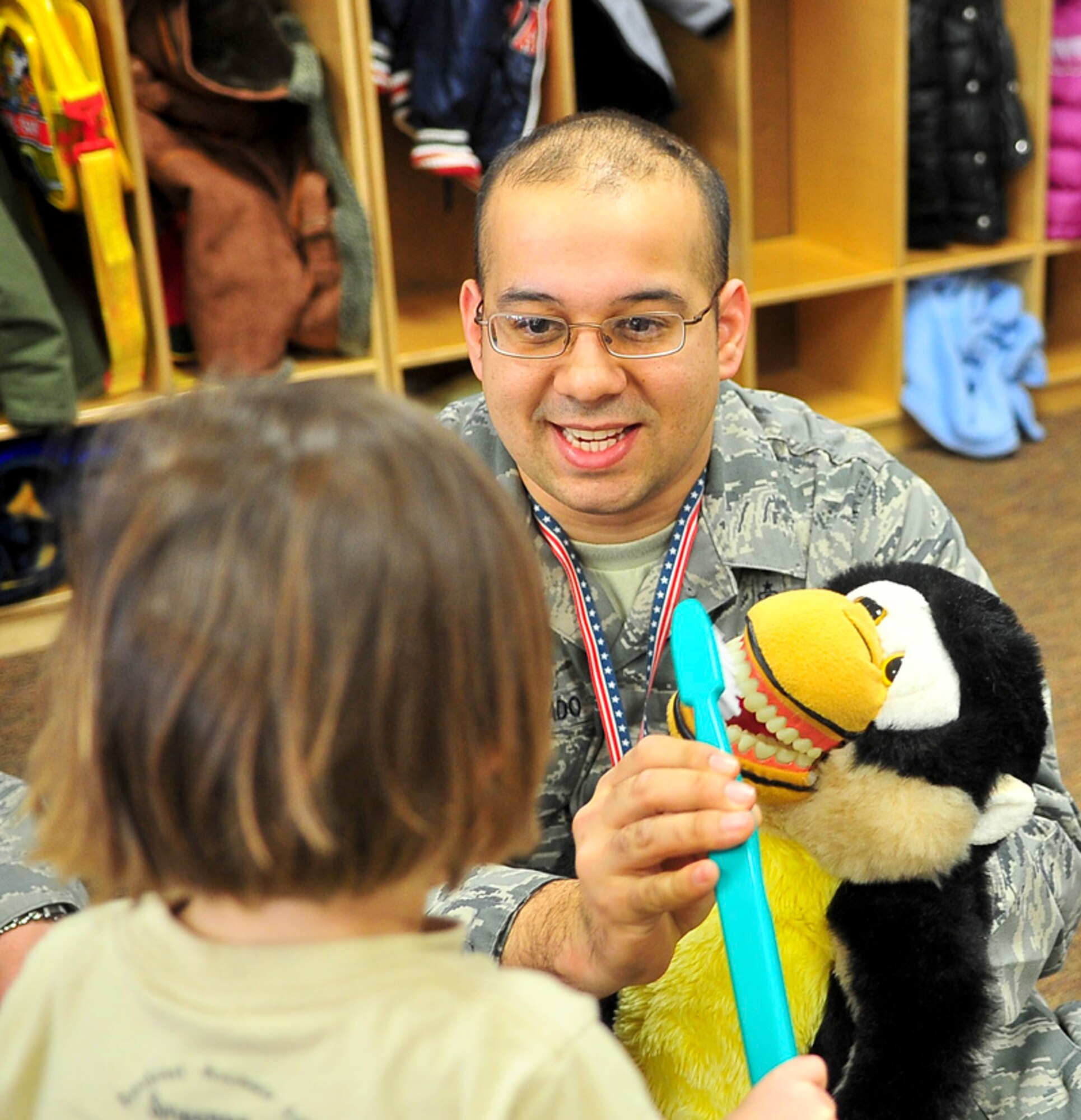 Tech Sgt. Francisco Maldonado, 51st Dental Squadron dental lab technician, hands a tooth brush to a child during oral hygiene demonstrations on Feb. 9, 2012. The month of February is designated as National Children’s Dental Health Month and  through our the month members of the 51st Dental Squadron will present oral hygiene briefings as well as distribute oral hygiene goody bags.  (U.S. Air Force photo/Senior Airman Adam Grant) 
