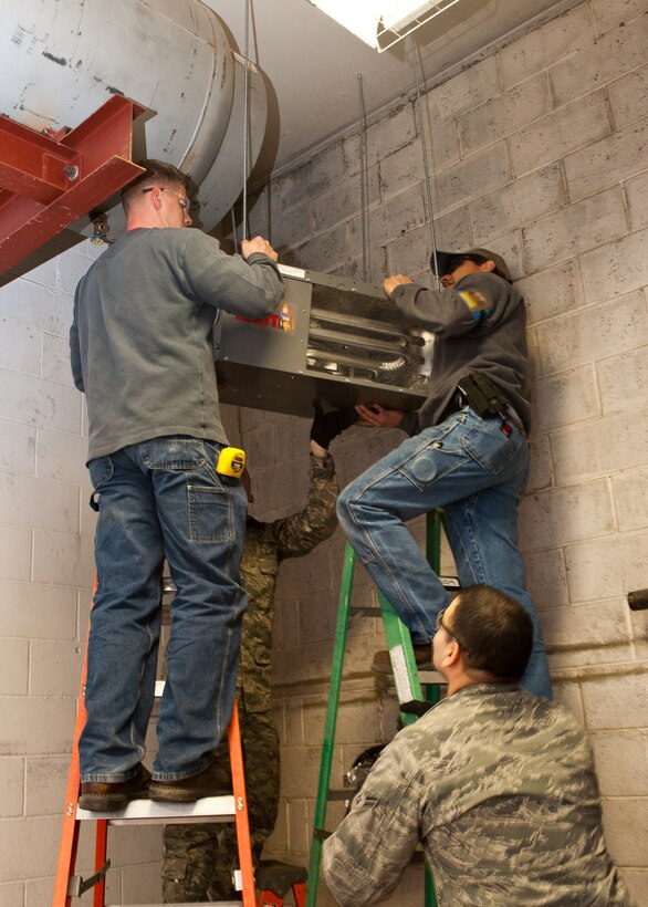 Members of the 28th Civil Engineer Squadron install a heating system into the maintenance room in dock 21 on Ellsworth Air Force Base, S.D., Feb. 2, 2012. By properly installing the system, technicians ensure efficient use and conservation of valuable resources in the facility. (U.S. Air Force photo by Airman Alystria Maurer/Released)