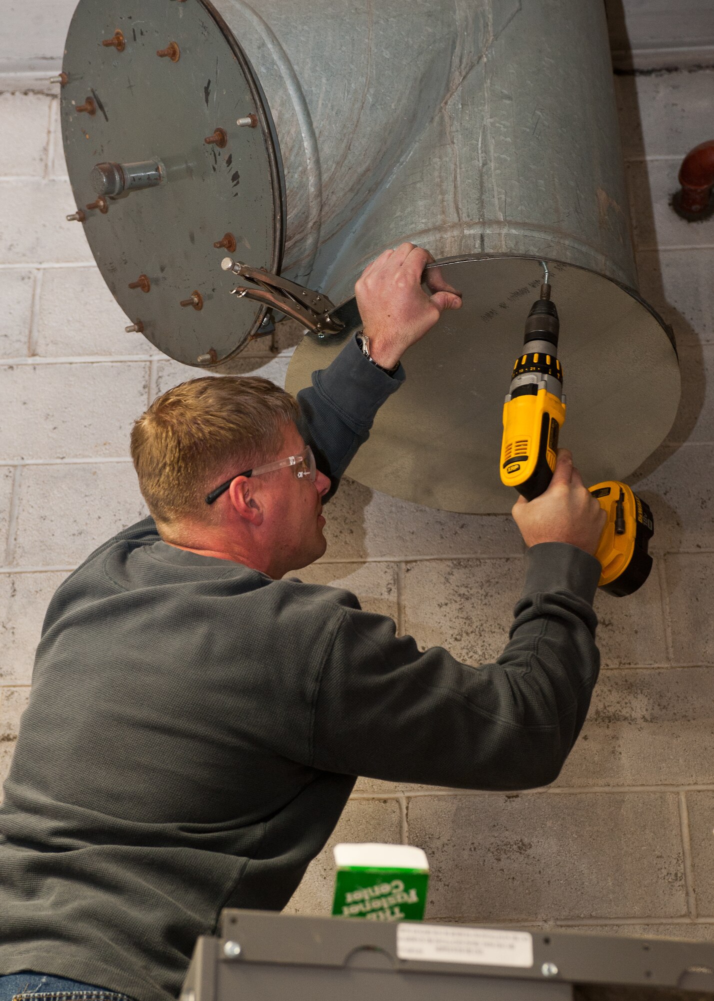 Michael Schmidt, 28th Civil Engineer Squadron heating and air conditioning technician, mounts sheet metal onto a vent to stop airflow during a heating system installation on Ellsworth Air Force Base, S.D., Feb. 2, 2012. The ducts in the room must be completely sealed to prevent the heat from escaping, which helps Ellsworth conserve resources. (U.S. Air Force photo by Airman Alystria Maurer/Released)    