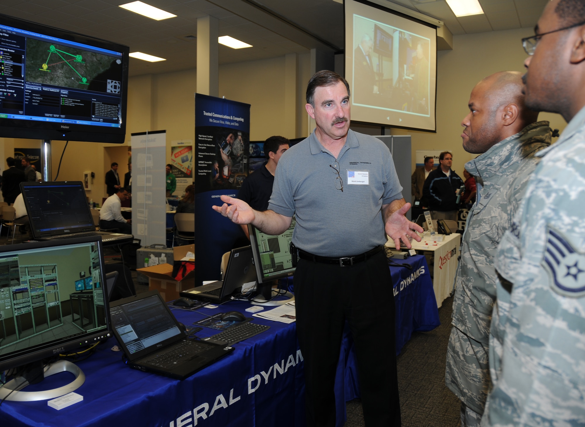 Mark Umberger, General Dynamics business development manager, provides a demonstration on network-centric training for networks and equipment to Tech Sgt. Doug Dredden, 336th Training Squadron, and Staff Sgt. Vincent Callahan, 81st Training Support Squadron, during a technology expo Jan. 9, 2012, at the Roberts Consolidated Aircraft Maintenance Facility, Keesler Air Force Base, Miss.  The 17th annual free expo, hosted by the 81st TRSS, featured more than 40 exhibitors.  (U.S. Air Force photo by Kemberly Groue)