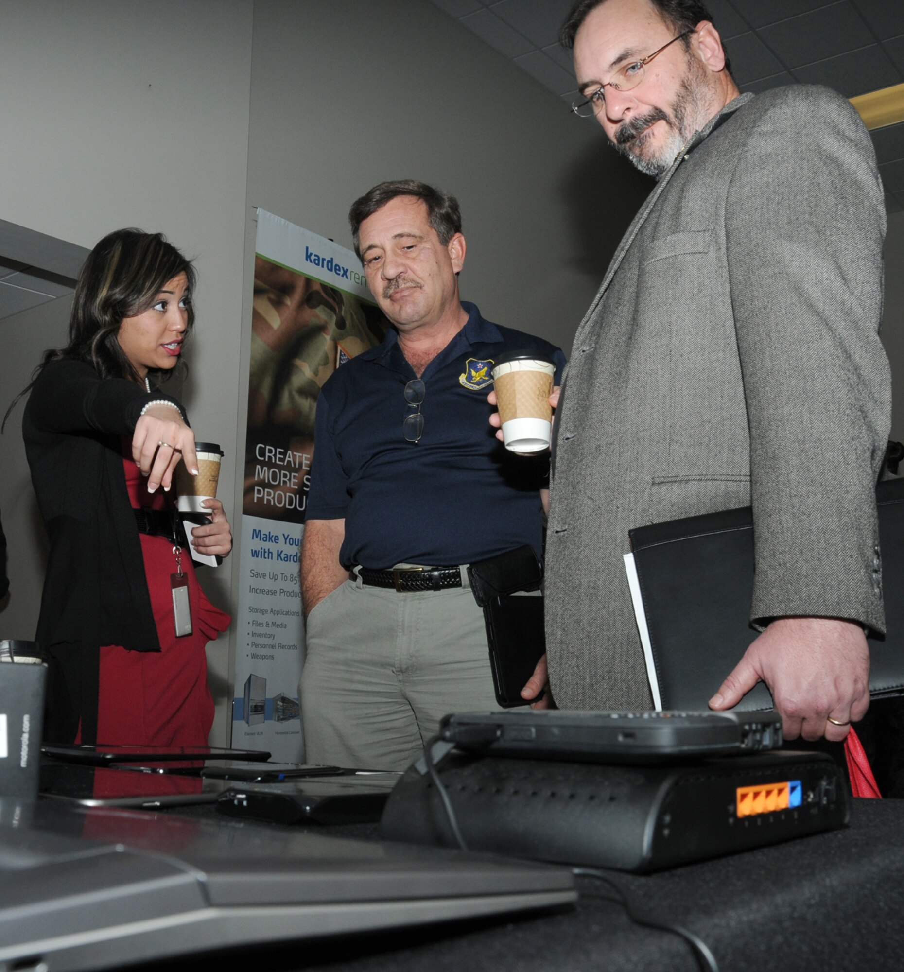 Colette Nieves, Sprint account manager, shows Ricky Collison and Steve Ellis, 2nd Air Force, various equipment Sprint offers during a technology expo Jan. 9, 2012, at the Roberts Consolidated Aircraft Maintenance Facility, Keesler Air Force Base, Miss.  The 17th annual free expo, hosted by the 81st Training Support Squadron, featured more than 40 exhibitors.  (U.S. Air Force photo by Kemberly Groue)