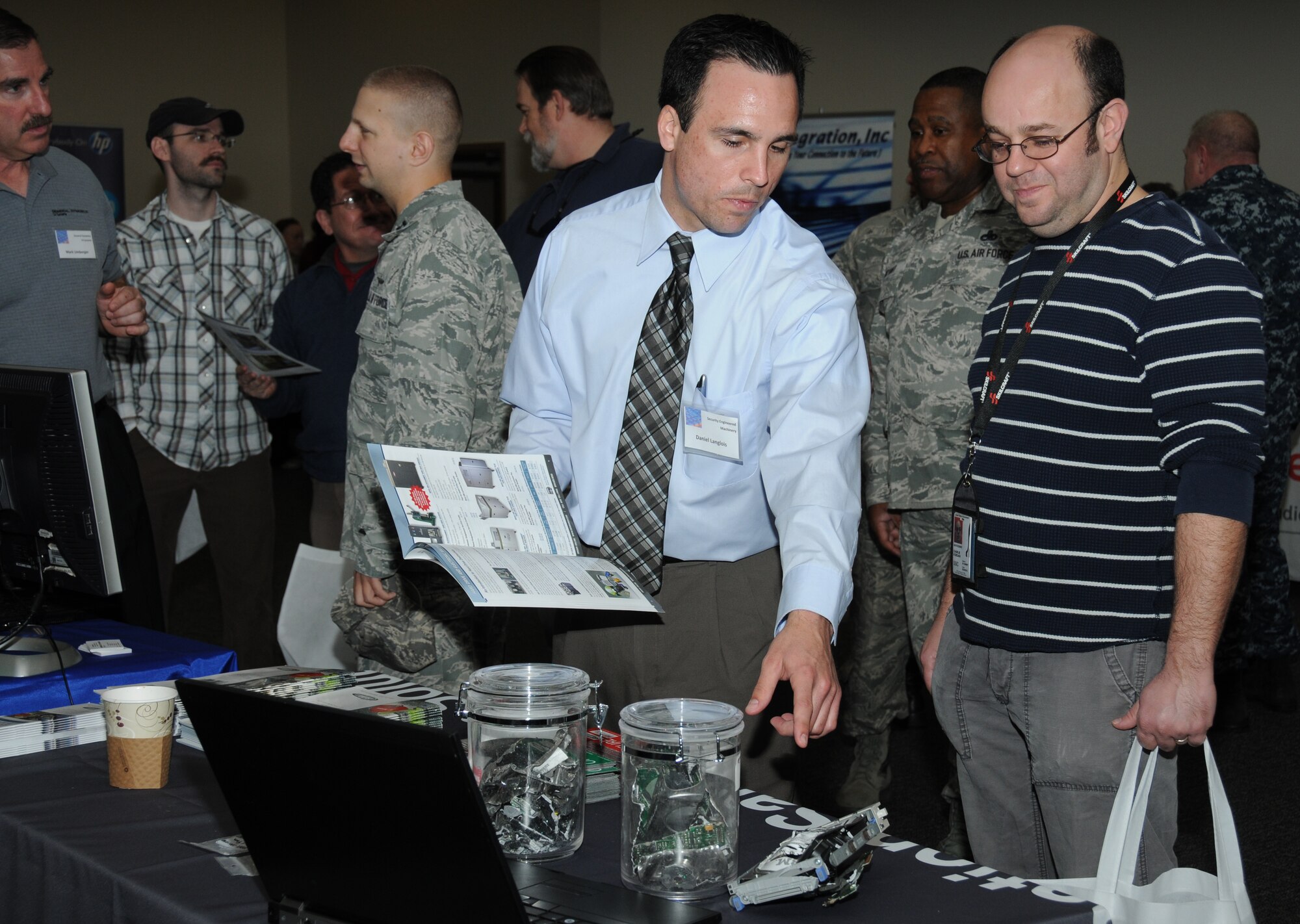 Daniel Langlois, Security Engineered Machinery territory sales representative, shows Charlie Kordahi, Stennis Space Center Naval Oceanographic Office, a variety of recycled items such as CDs during a technology expo Jan. 9, 2012, at the Roberts Consolidated Aircraft Maintenance Facility, Keesler Air Force Base, Miss.  The 17th annual free expo, hosted by the 81st Training Support Squadron, featured more than 40 exhibitors.  (U.S. Air Force photo by Kemberly Groue)