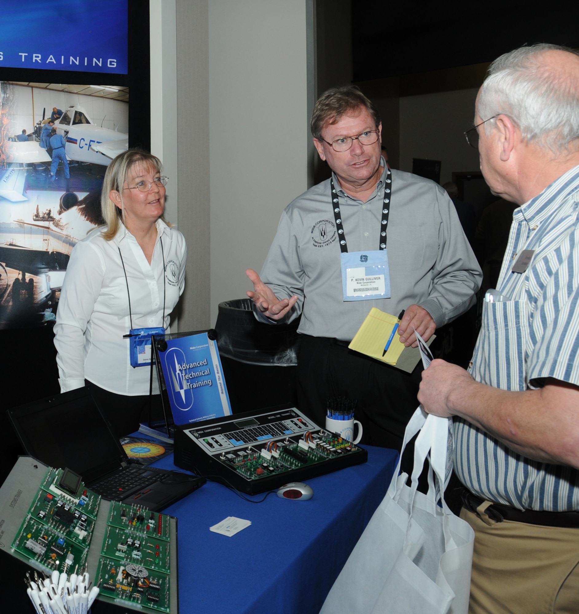 Joann and Kevin Gulliver, NIDA Corporation, provide information about systems trainers used for basic and advanced electronics to Brendan Davidson, 335th Training Squadron, during a technology expo Jan. 9, 2012, at the Roberts Consolidated Aircraft Maintenance Facility, Keesler Air Force Base, Miss.  The 17th annual free expo, hosted by the 81st Training Support Squadron, featured more than 40 exhibitors.  (U.S. Air Force photo by Kemberly Groue)