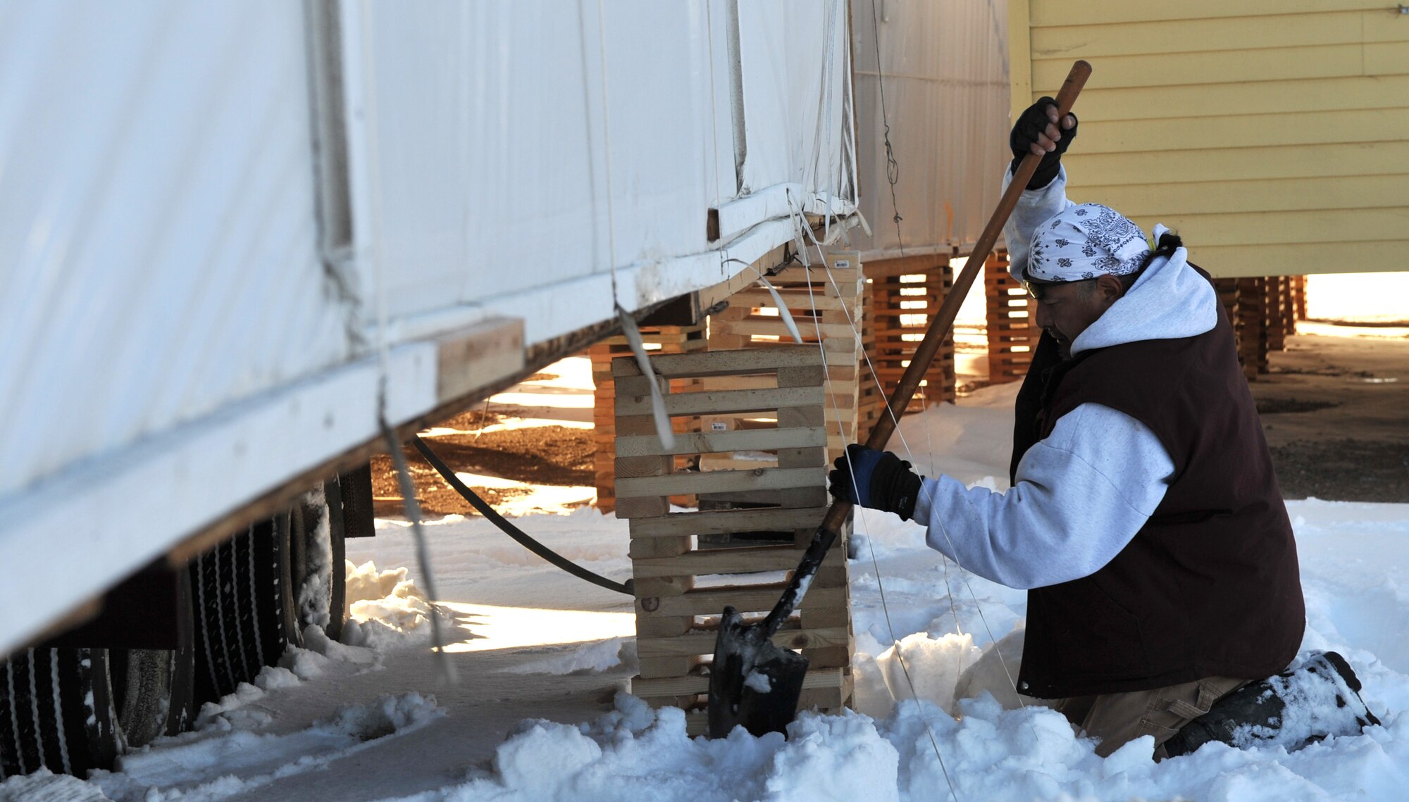 Dennis Butterfly, civic engineer for Ely Shoshone housing, digs out snow and dirt to make the ground level, Jan. 25, 2012, in Ely, Nevada. The houses are brought in on a flatbed truck and a temporary platform is made to keep them off the ground until a proper foundation is built. (U.S. Air Force photo by Airman 1st Class Heather Hayward/Released)