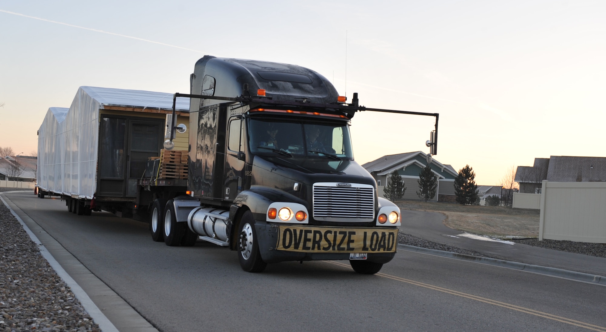 A truck drives part of a home through base housing Dec. 16, 2011, at Mountain Home Air Force Base, Idaho. After leaving the base and travelling more than 300 miles, it will be placed onto a temporary foundation until a permanent foundation is laid by contracted members of the tribe. (U.S. Air Force photo by Airman 1st Class Heather Hayward/Released)