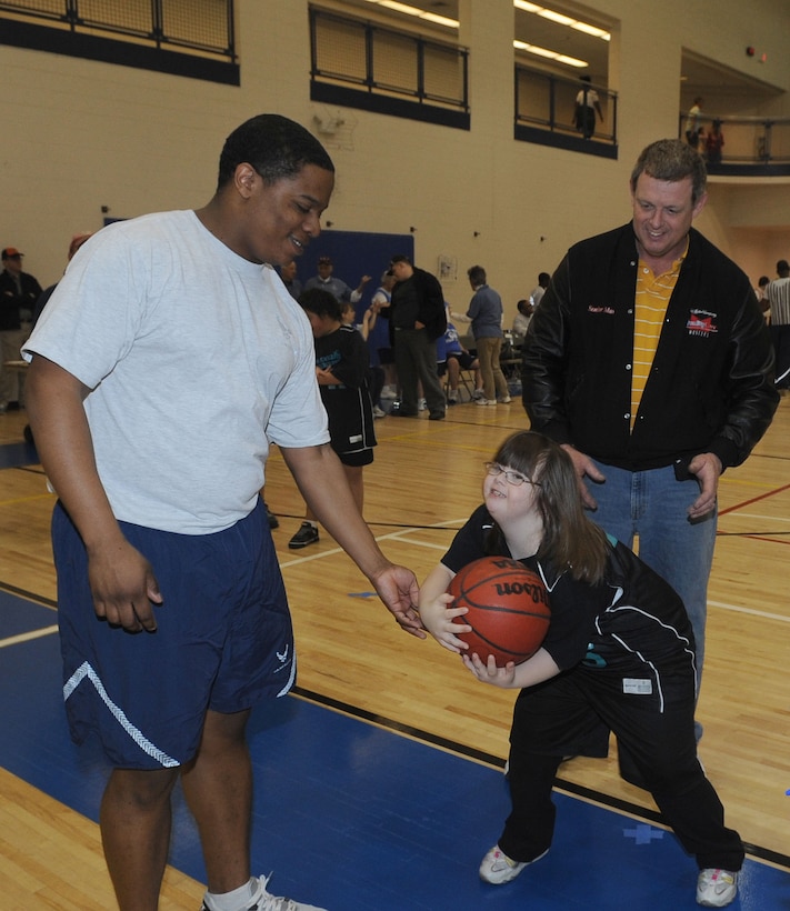 U.S. Air Force Staff Sgt. Daniel Smith, 30th Intelligence Squadron, hands a ball to Katie Kelso during a Special Olympics basketball game at Langley Air Force Base, Va., Feb. 11, 2012. Special Olympics provides year-round sports training and athletic competition in a variety of Olympic-type sports for children and adults with intellectual disabilities. (U.S. Air Force photo by Airman 1st Class Racheal Watson/Released)
